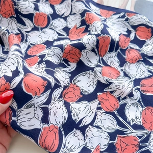 Detail of navy blue silk scarf with red tulip floral print and herringbone twill texture
