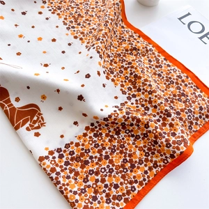 Gros plan du foulard en soie à fleurs avec bordures oranges et texture satinée lisse