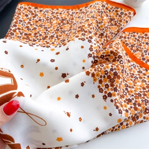 Gros plan du foulard en soie fleurie montrant le sergé et les bords roulés orange