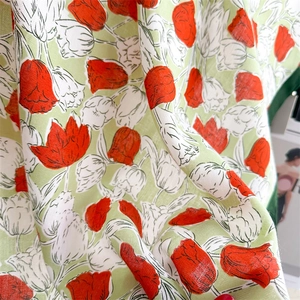 Detailed close-up of light green silk scarf with red tulip prints and herringbone texture