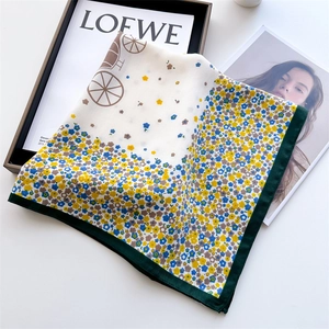 Détail d'un foulard en soie à fleurs avec imprimé carrosse et ourlet vert contrasté
