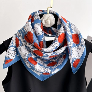 Detail of red tulip silk scarf tied on black top with white camellia brooch accessory