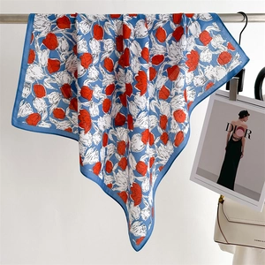 Elegant blue silk square scarf with red tulip prints hanging on a metal rod