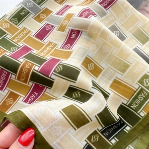 Detail shot of the vintage green silk scarf with chevron patterns and fashion lettering