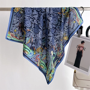 Detail of blue paisley silk scarf showing soft drape and luxurious satin texture