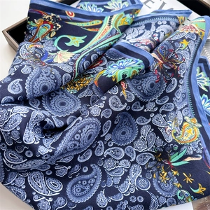 Detailed view of luxury paisley silk scarf with deep blue tones and floral patterns