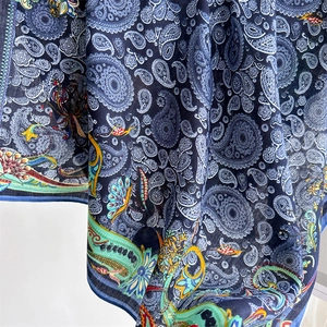 Macro shot of silk-like blue scarf showing intricate white paisley patterns and draped texture