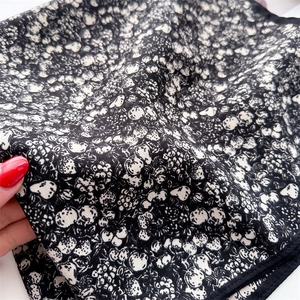 Detailed view of black floral silk scarf with white pattern and premium edge stitching