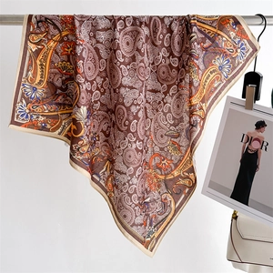 Detail of luxury paisley pattern silk scarf draped elegantly next to a fashion magazine