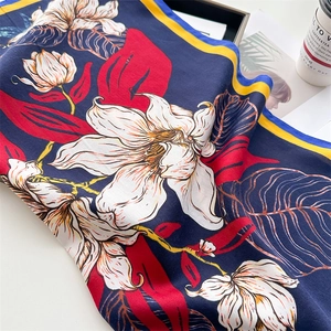 Detail of silk-like navy scarf with realistic white floral prints and yellow borders