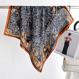 Detail of paisley silk scarf with orange borders hanging next to a fashion handbag