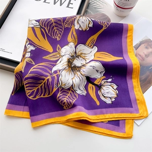Elegant purple lily floral print silk scarf with yellow borders on a marble surface