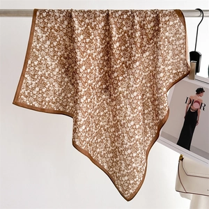 Detail of floral brown silk scarf with delicate drape and smooth satin texture finish