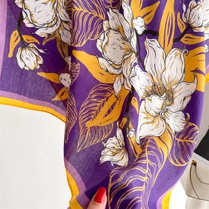 Detail of purple lily print scarf showing textured fabric and yellow edge stitching