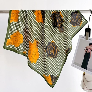 Detailed close-up of green and white houndstooth silk scarf with vibrant floral patterns