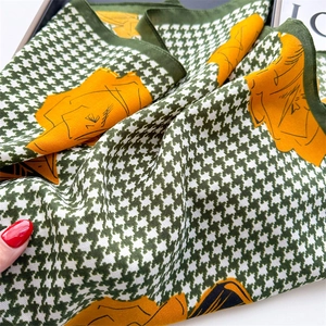Close-up of houndstooth silk scarf featuring yellow floral patterns and fine hand-rolled edges