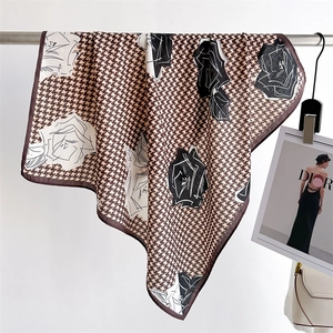 Elegant houndstooth and rose floral silk scarf in coffee beige, shown in a stylish display