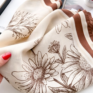 Detailed macro view of retro floral silk scarf featuring daisy patterns and twill texture