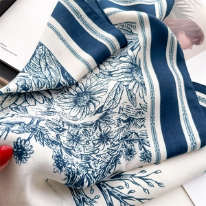 Detail showing the vintage floral pattern and silk texture on the blue square scarf