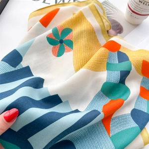 Detail of silk scarf with orange horse print and geometric patterns showing soft texture