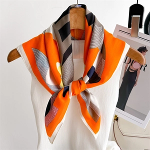 Orange silk square scarf with geometric horse print on a wooden hanger with magazine