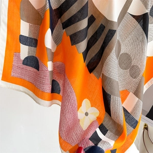 Detail of orange geometric scarf showing high-quality fabric texture and fine edge stitching