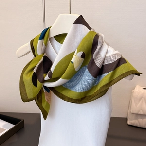Detail showing herringbone texture and abstract geometric print on a green silk scarf