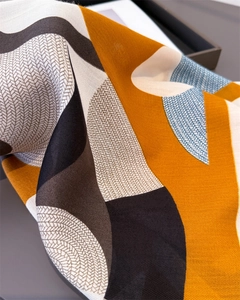 Close-up of orange silk scarf featuring a detailed herringbone weave and horse print