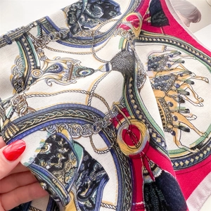 Close-up of silk-textured square scarf featuring vintage equestrian chain and belt prints
