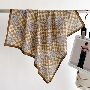 Detail of coffee and beige checkered silk scarf with swirl patterns on a metal rod