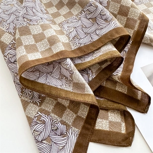 Detail of silk scarf showing brown checkerboard pattern and purple abstract floral design