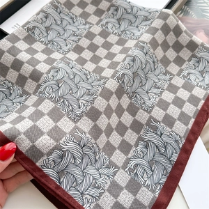 Macro detail of houndstooth silk scarf featuring silver geometric lines and red edges