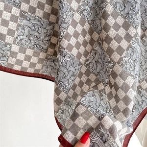 Detail of houndstooth silk scarf showing red contrast edge and drape texture
