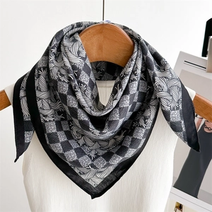Detail of black and white houndstooth silk scarf hanging on a wooden hanger with tank top