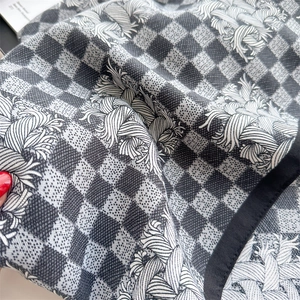 Detail shot of houndstooth silk scarf with wave patterns and black stitched edges