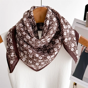 Detail of floral silk scarf draped over a wooden hanger with brown and white patterns