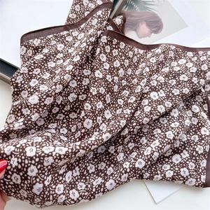 Detail of coffee brown floral silk scarf showing light texture and dark border