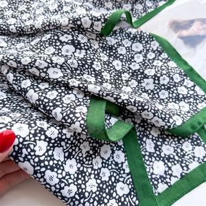Detailed macro view of black and white floral pattern with green herringbone border