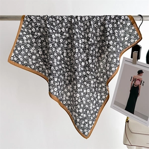 Detail of floral print silk scarf featuring monochrome patterns and brown hemmed edges