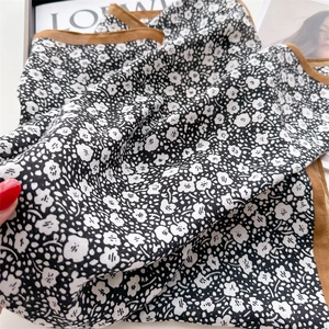Close-up of lightweight floral scarf with black and white print and yellow border