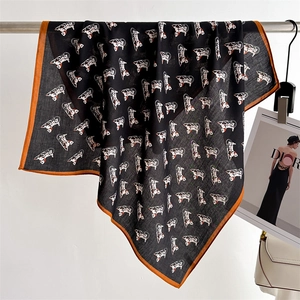 Close-up of square silk scarf featuring a black French bulldog print and orange borders