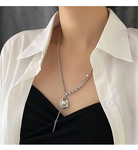 Détail d'un collier de perles argenté avec chaîne pavée asymétrique porté par un mannequin