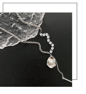 Détail du collier à pendentif coquillage argenté avec perle sur pierre noire