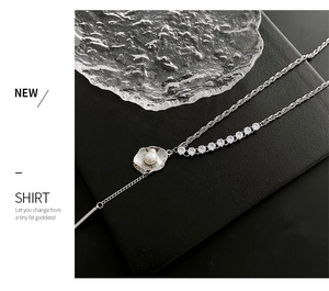 Détail macro d'un pendentif coquillage argenté avec perle et zircon sur une chaîne