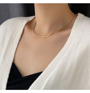 Gros plan d'un collier chaîne serpent dorée porté par un mannequin pour l'élégance