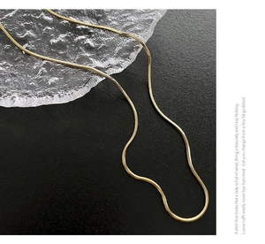 Gros plan d'une chaîne serpent plaquée or 18 carats avec texture métallique fine et brillante