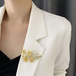 Elegant gold flower brooch with yellow crystals pinned on a white blazer lapel