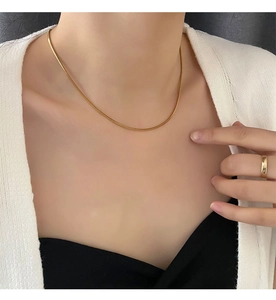 Gros plan d'un collier chaîne serpent carrée plaqué or 18 carats sur le cou du mannequin
