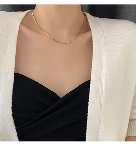 Détail d'un collier chaîne serpent plaqué or 18 carats minimaliste sur le cou d'un mannequin