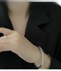 Détail d'un bracelet boucle en zircon argenté et bague dorée sur un mannequin femme